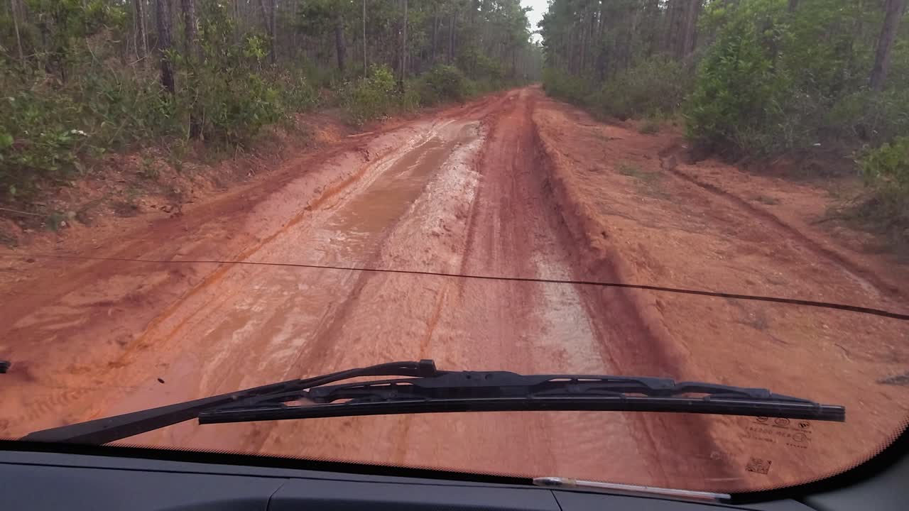pov de un autobús que conduce por un camino de barro húmedo y rojo en honduras