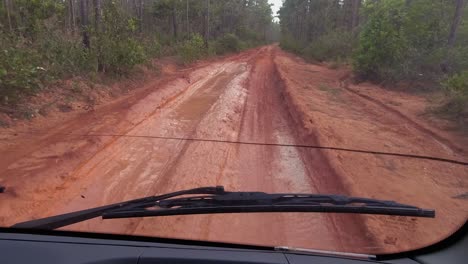POV-from-bus-driving-on-deeply-rutted,-red-wet-mud-road-in-Honduras
