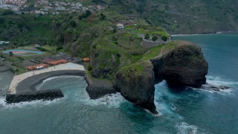 aerial pullback from guindaste viewpoint in madeira portugal, secluded cove and cliff