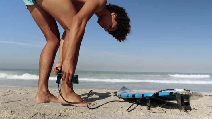 Giovane surfista che lega il leash della tavola da surf 4k