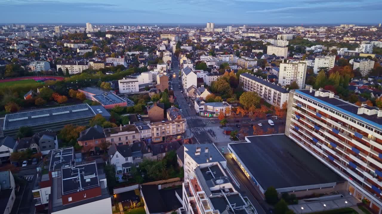 Nighttime city lights illuminate buildings and streets creating a calm urban atmosphere across Rennes, Maurepas neighborhood. Aerial drone panoramic
