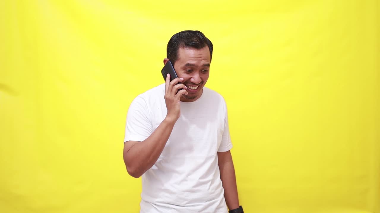 안심 한 아시아 성인 남자가 전화 로 이야기 하는 동안 그의 성취 를 축하 하고 있다