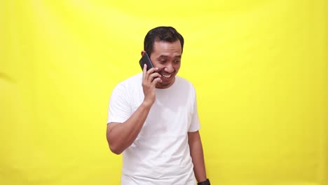 Relieved-Asian-adult-man-celebrating-his-achievement-while-talking-on-the-phone