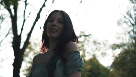 Portrait-of-a-gorgeous-hispanic-latino-young-woman-looking-at-the-camera-and-show-emotions-from-serious-to-smiling-and-laughing-with-a-beautiful-British-park-in-the-background-at-golden-hour