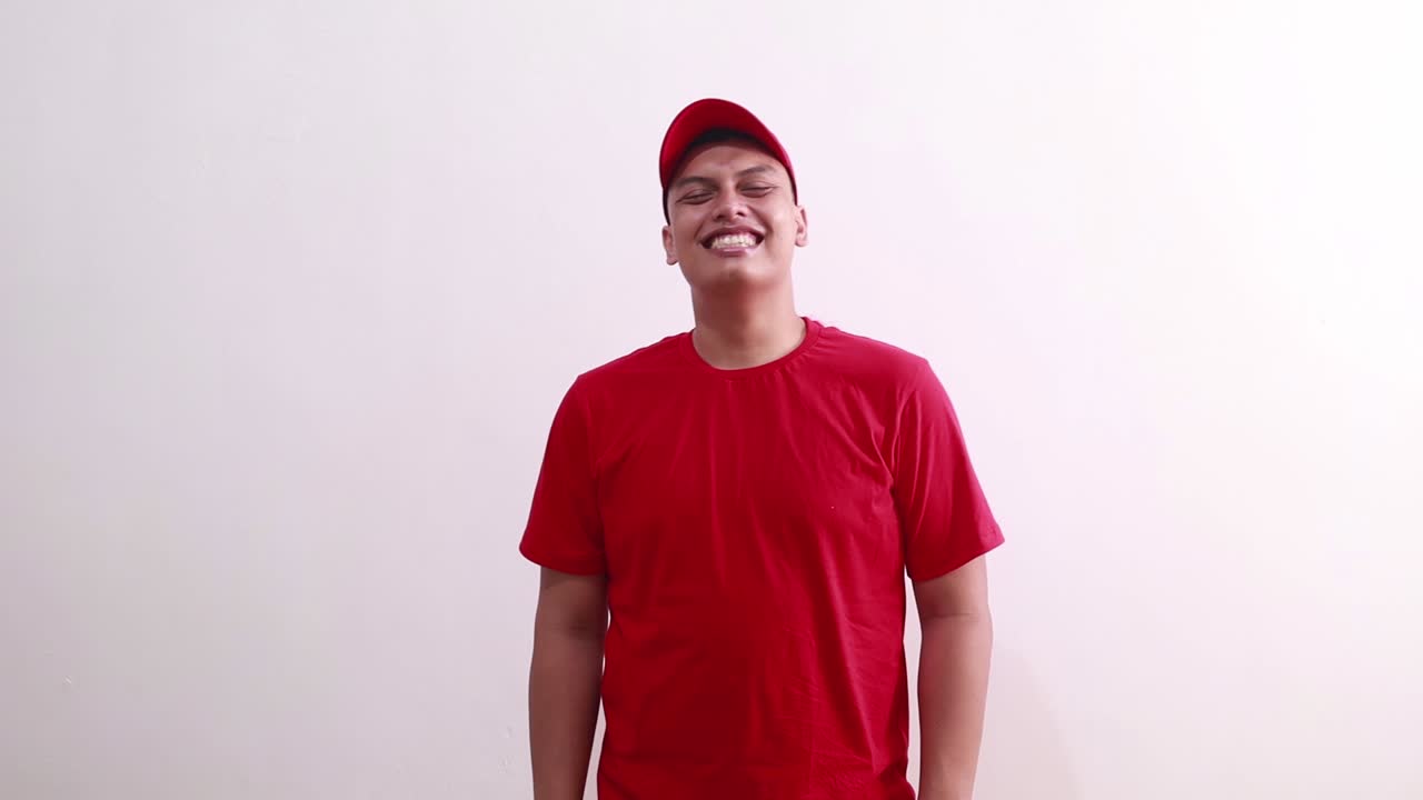 joven asiático guapo en rojo de pie mientras se ríe