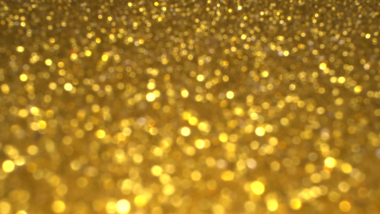 Guld bokeh feriebaggrund til en jule- og nytårsfest. Magisk skinnende tekstur, glimmer og lys.