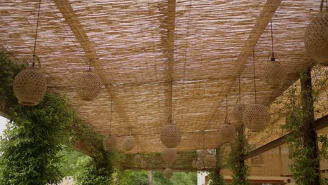 pérgola rústica con persianas y linternas de bambú, rodeada de exuberante vegetación