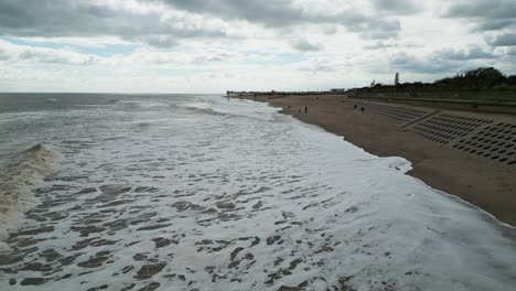 Typischer-Englischer-Badeort,-Aufgenommen-Mit-Einer-Drohne,-Die-Einen-Hohen-Luftbildpunkt-Bietet,-Der-Einen-Weiten-Sandstrand-Mit-Einem-Pier-Und-Tosenden-Wellen-Zeigt-2