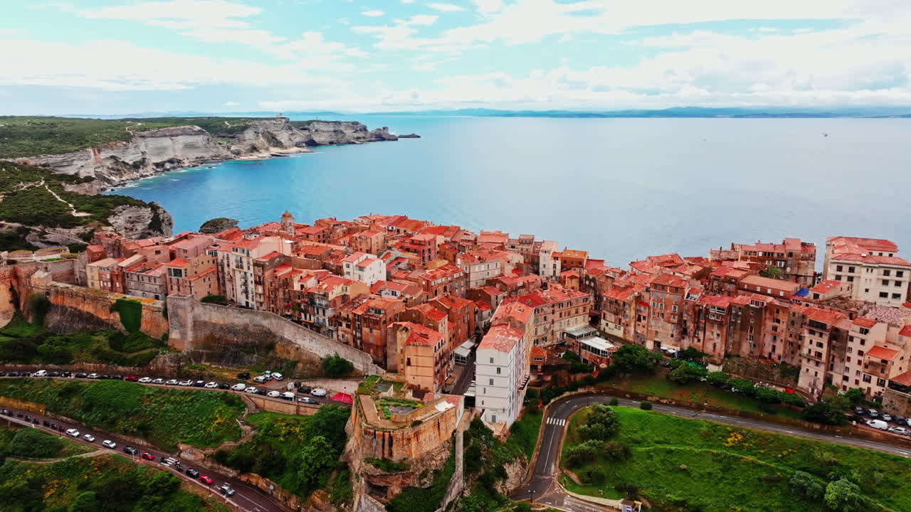 Aerial drone shot over the historic coastal town of Bonifacio in Corsica, France. High view of the rocky steep cliff and the turquoise sea. Ancient Citadel overlooking the rugged coastline