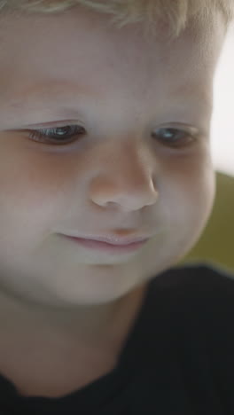 blue eyed toddler child watch video on glowing device screen at home closeup. tranquil little boy enjoys amusement on internet. domestic education