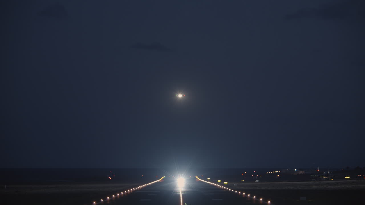 una vista nocturna de una pista de aterrizaje con un avión despegando