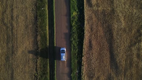 aerial vertical view in 4k of parked minivan on a dusty dirt road in canada's countryside