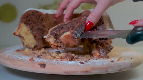 pastel de mármol tradicional en plato de madera, manos femeninas cortando pastel en rodajas