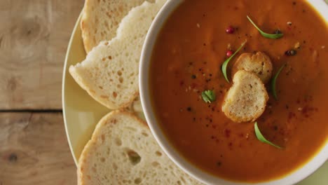 video of cream tomato soup in bowl on wooden table with bread