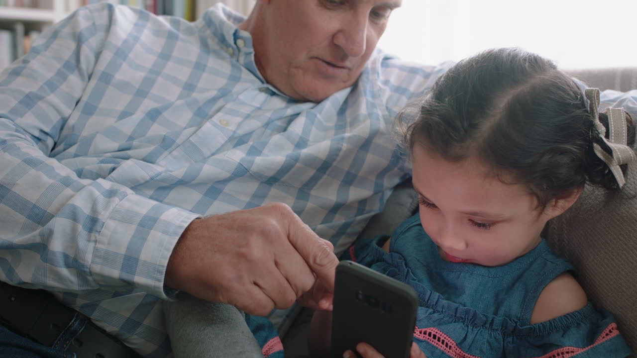abuelo feliz mostrando a la niña cómo usar el teléfono inteligente enseñando a la nieta curiosa tecnología moderna niño inteligente aprendiendo teléfono móvil sentado con el abuelo en el sofá