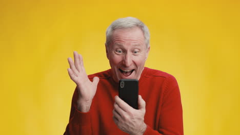 senior man excitedly using smartphone