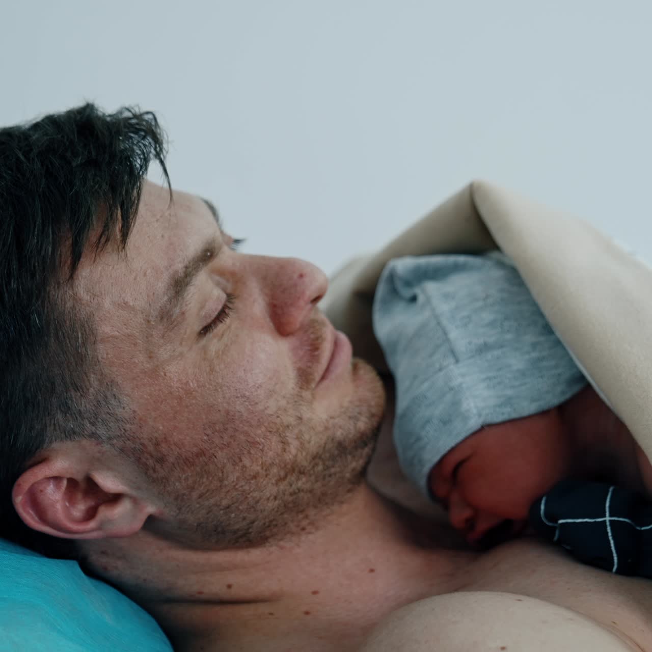 Caucasian dad is happy to hold his just born child. The baby is put on father's chest for skin to skin contact