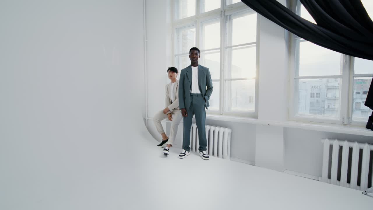 Two men in suits posing in front of a window