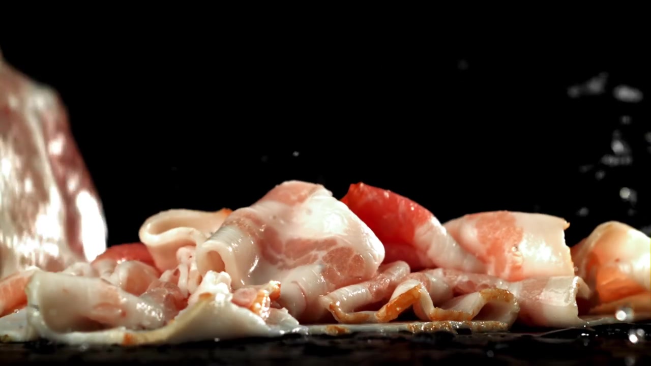 Fetta di pancetta cruda che cade e schizza al rallentatore
