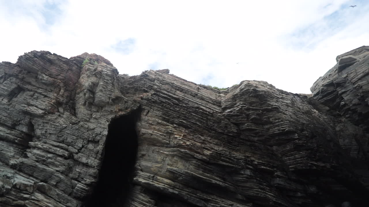 Dramatic cliffs with layers of textured rock formations beneath a cloudy sky