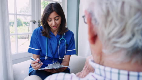 Over-shoulder-view-of-nurse-on-home-visit-with-senior-man