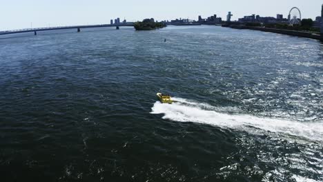 a jet boat racing across the st. lawrence river in montreal, offering tourists an adrenaline-fueled ride. the river's waves and the city skyline create an exhilarating scene. tourist destination.