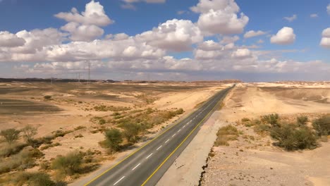coche zoomando hacia el norte en una carretera del desierto con cielo azul nublado