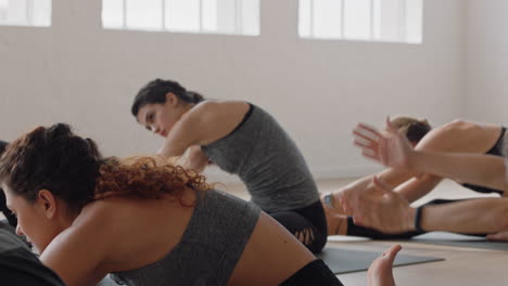 healthy yoga woman practicing seated side bend pose young caucasian female enjoying fitness lifestyle exercising in studio with group of multiracial women