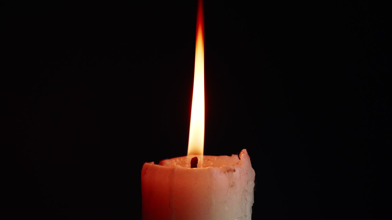 Le luci di singole candele colorate su sfondo nero con effetto di luce e slow motion.