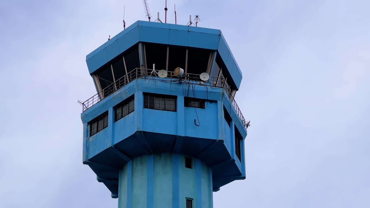 Close-up of a blue air traffic control tower with antennas and satellite dishes, ideal for aviation, transportation, and airport-themed media projects