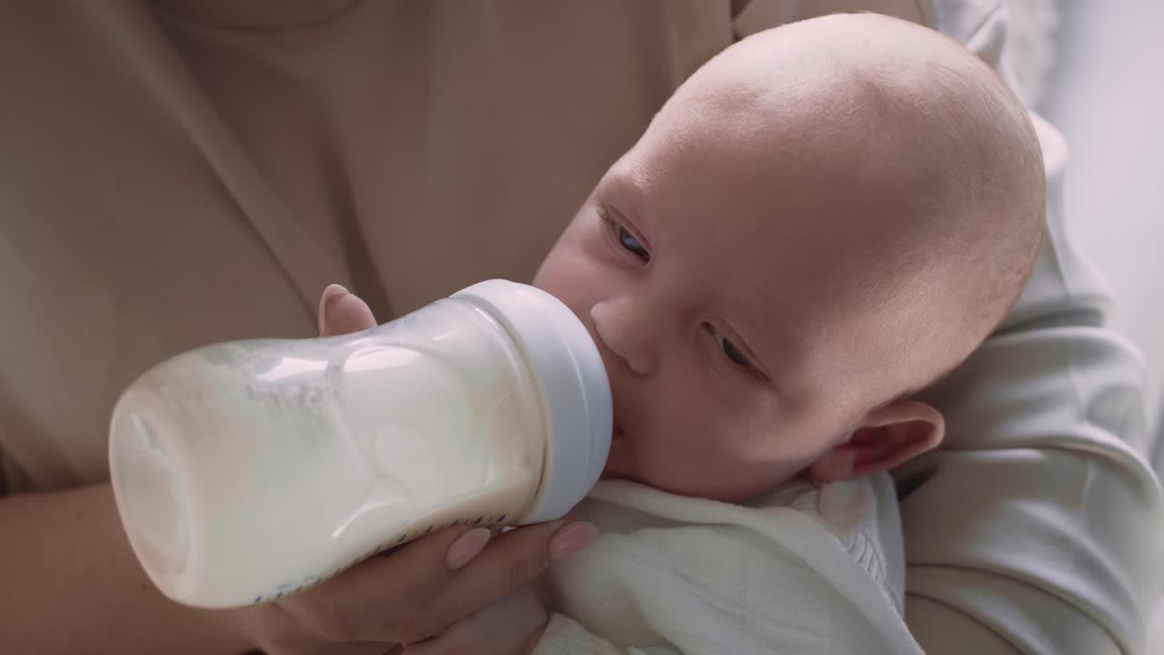 madre alimentando al bebé con un biberón