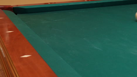 closeup of person playing pool addressing and quickly shooting purple stripe 12 ball into corner pocket after practice strokes using cue ball, open bridge hand with wooden cue stick and green felt