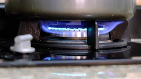 a cooking stove using gas with a fire on the burner and a pot on top