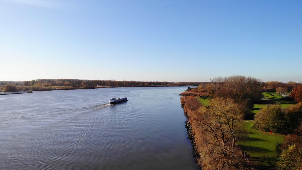 antena que se eleva desde la ruta otoñal junto al oude maas con el barco pasando en segundo plano.
