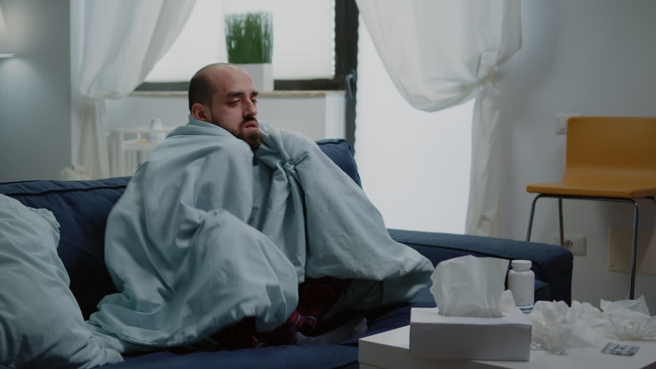 Person with flu feeling cold and shivering wrapped in blanket