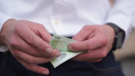 young businessman with watch at his wrist counting hundret euro banknotes