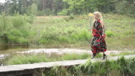 Mujer-Atractiva-Con-Vestido-Largo-Corriendo-Por-Un-Pequeño-Puente-Cruzando-Un-Estanque