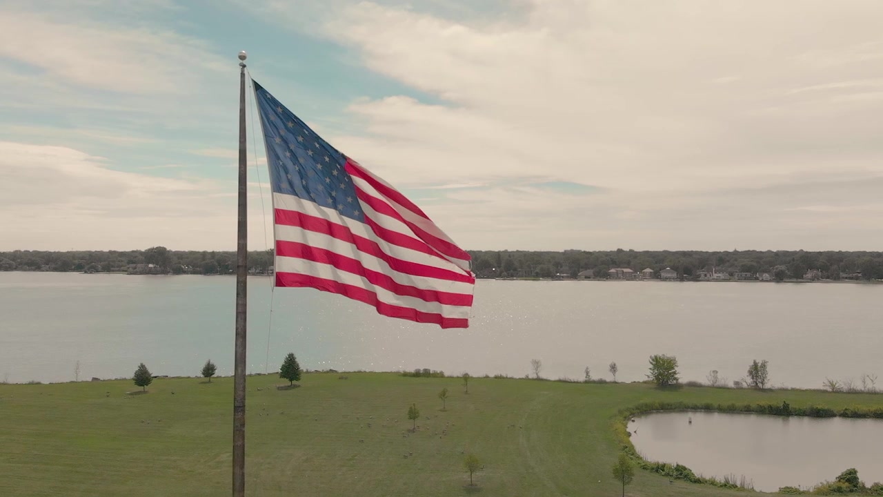 Bendera Amerika Berkibar di Tiang Bendera di Tepi Danau