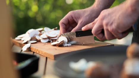 young-man-cutting-mushrooms-on-wooden-board-in-the-garden-close-up