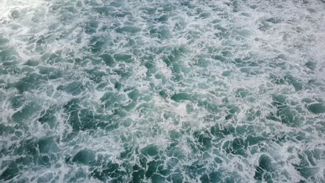 drone flying over foaming waves breaking in open blue sea, revealing cloudy horizon. beautiful ocean foam background