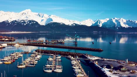 4k drone video of seward boat harbor and surrounding snow covered mountains on snowy winter day in alaska