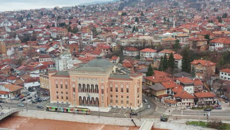 Bunte-Straßenbahn-Vor-Dem-Rathaus-Von-Sarajevo-Am-Damm-Des-Flusses-Miljacka-In-Bosnien-Und-Herzegowina
