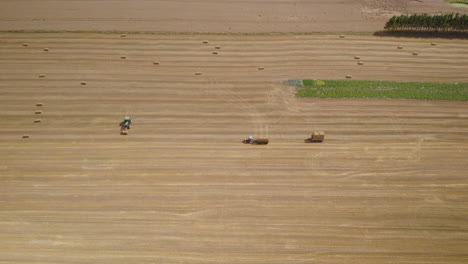 Agricultores-Que-Trabajan-En-Un-Campo-De-Heno,-Cargando-Pacas-Cuadradas-En-Un-Remolque-De-Tractor