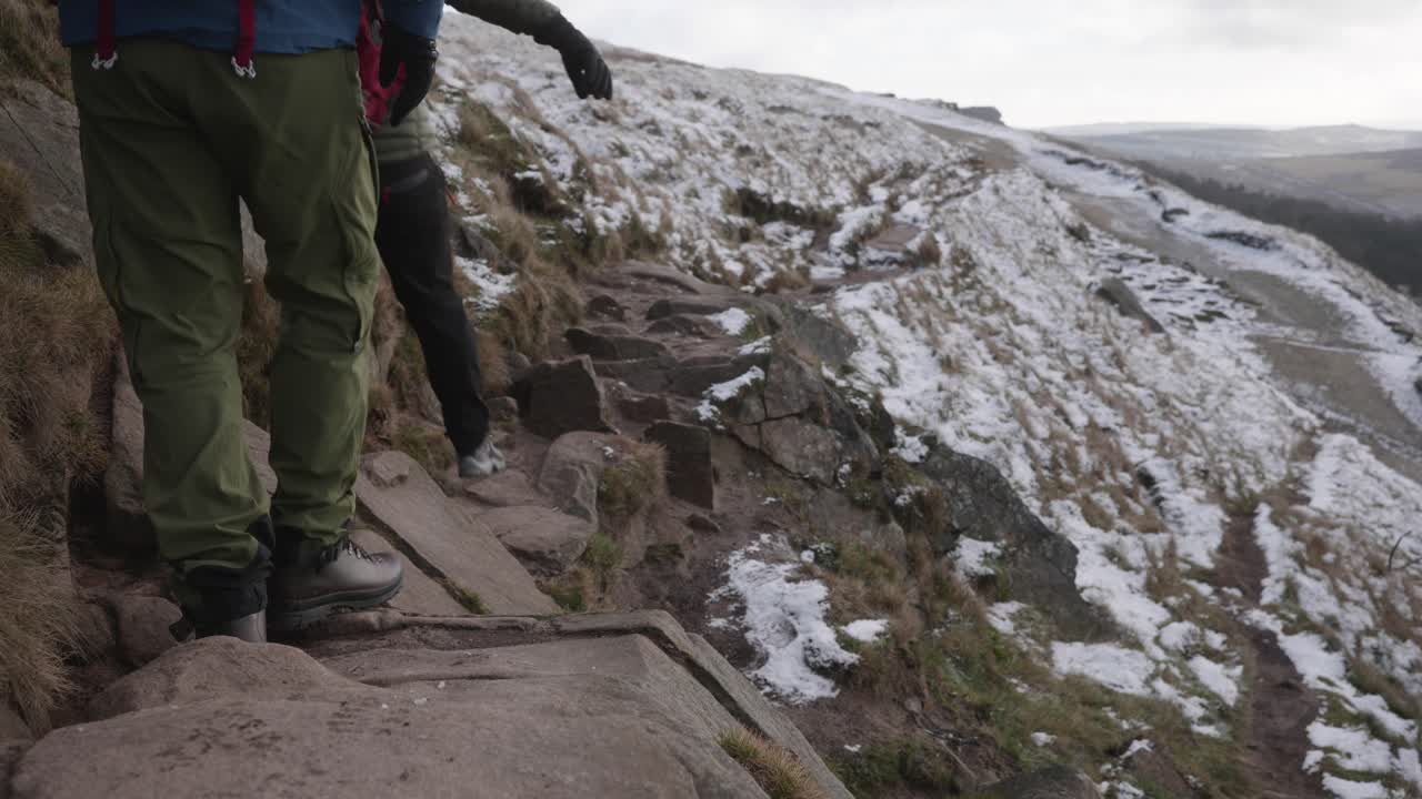 Two men hiking and scrambling over rocks on a trail in frozen, winter, snowy terrain