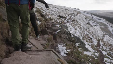 two men hiking and scrambling over rocks on a trail in frozen, winter, snowy terrain