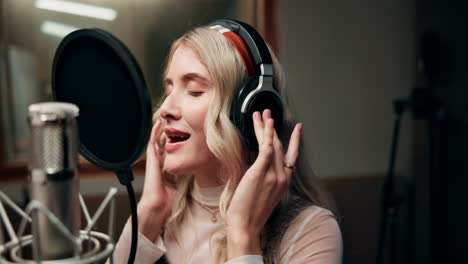 woman recording music in studio with microphone and headphones