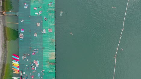 birds eye aerial view, pontoon at lakefront of perucac lake serbia, people enjoying in water and sun on summer day