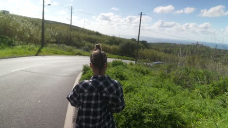 woman walking on a winding road in a countryside landscape