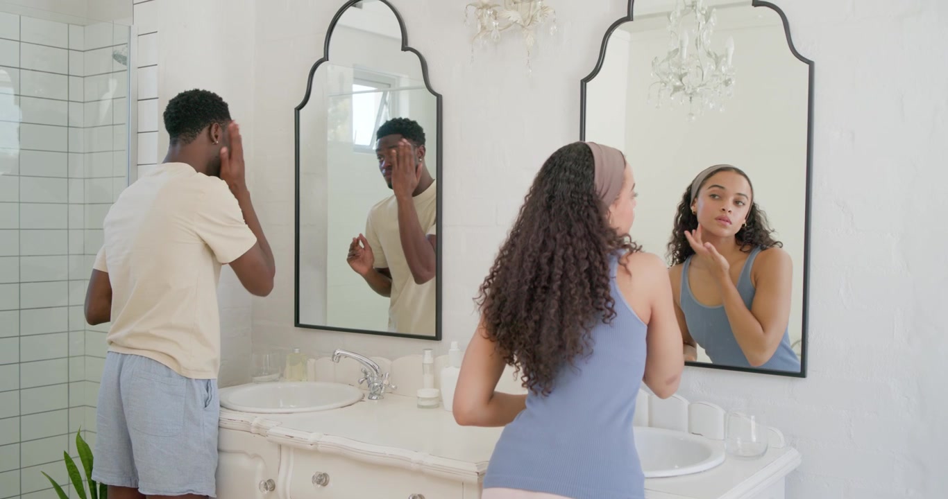 Coppia afroamericana che si prepara davanti a un doppio lavabo in marmo, l'uomo si strofina la mascella mentre la donna si tampona gli occhi