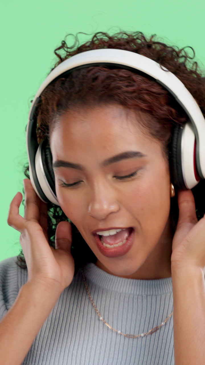 Donna felice che ascolta musica con le cuffie su schermo verde